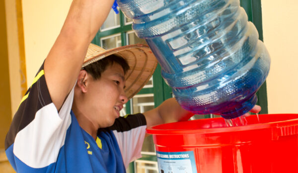 Woman putting water into bucket